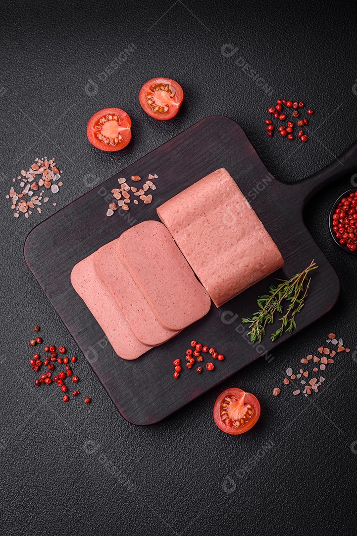 Delicioso presunto rosa enlatado com sal, especiarias e ervas sobre um fundo escuro de concreto