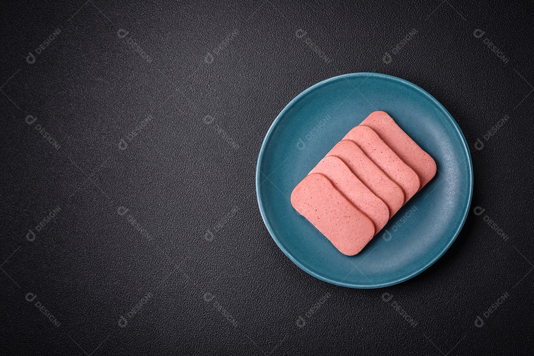 Delicioso presunto rosa enlatado com sal, especiarias e ervas sobre um fundo escuro de concreto