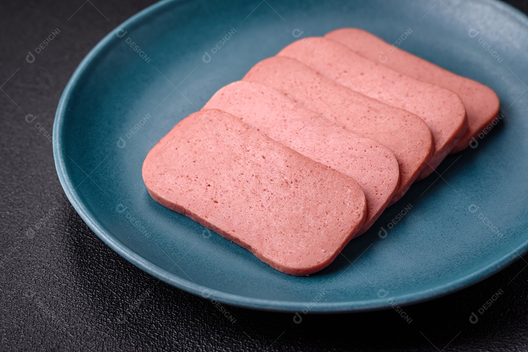 Delicioso presunto rosa enlatado com sal, especiarias e ervas sobre um fundo escuro de concreto