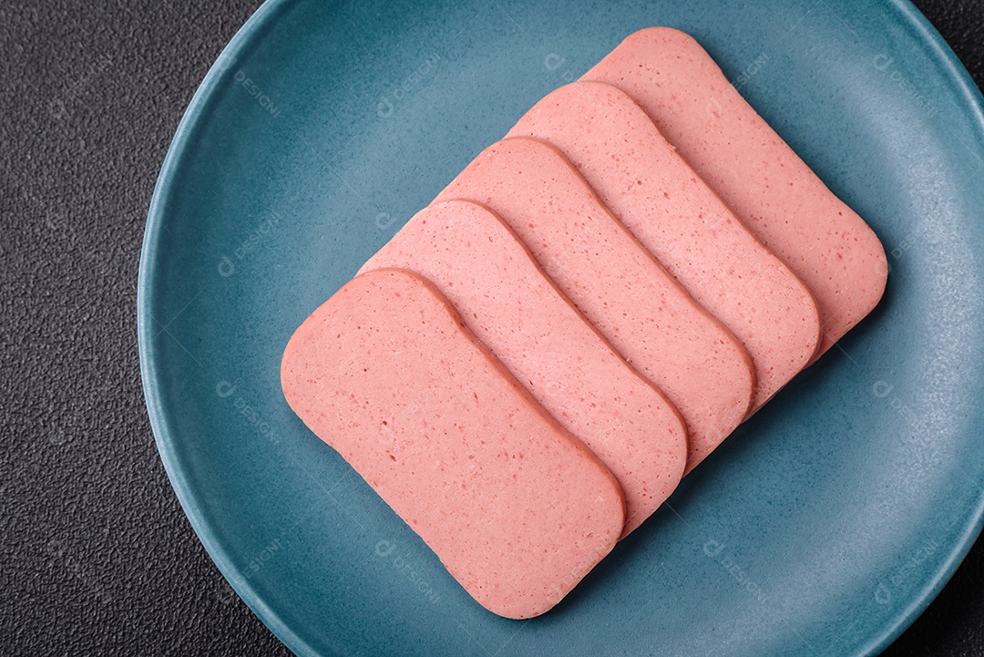 Delicioso presunto rosa enlatado com sal, especiarias e ervas sobre um fundo escuro de concreto