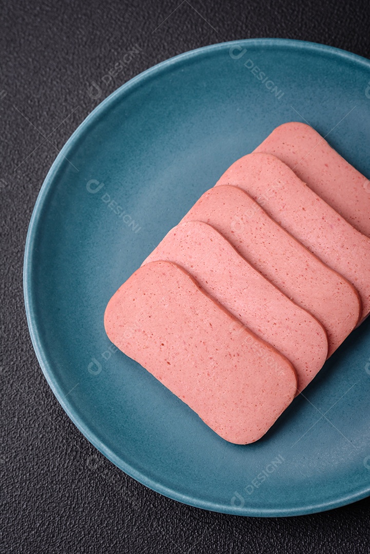 Delicioso presunto rosa enlatado com sal, especiarias e ervas sobre um fundo escuro de concreto