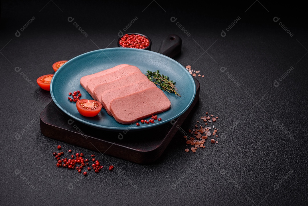 Delicioso presunto rosa enlatado com sal, especiarias e ervas sobre um fundo escuro de concreto