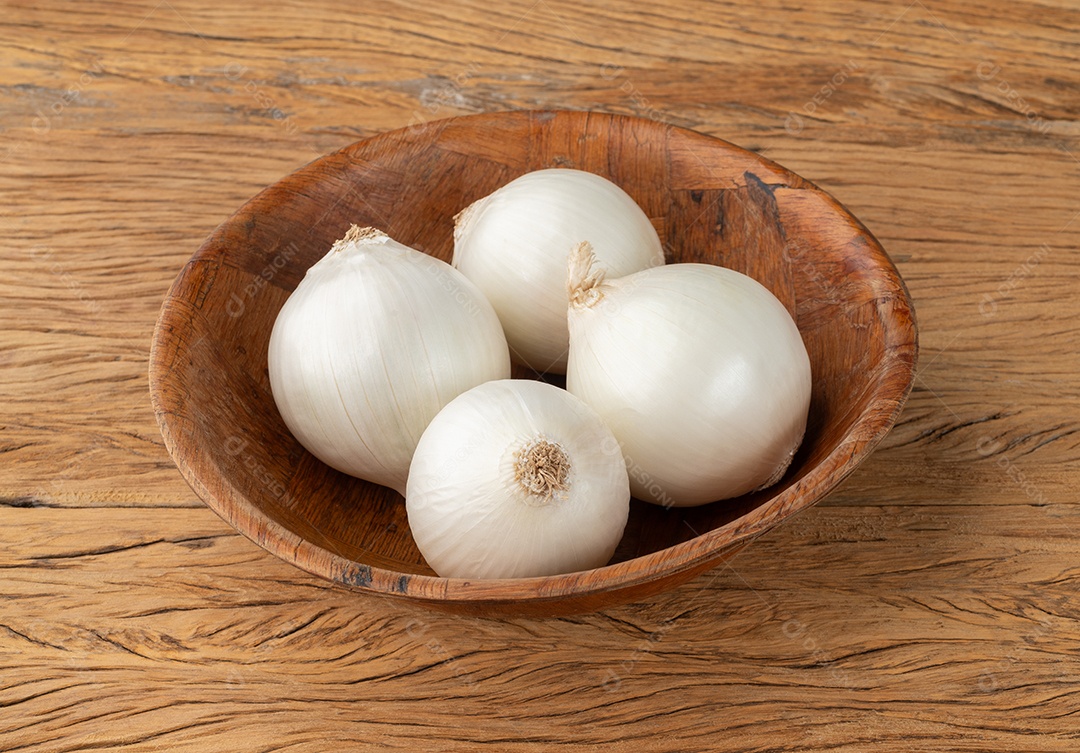 Cebolas branca em uma tigela sobre a mesa de madeira
