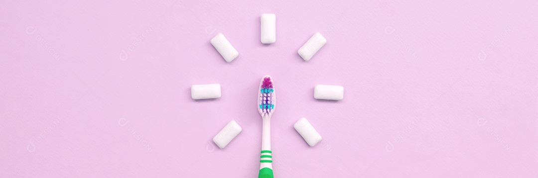Escovas de dentes e gomas de mascar estão sobre fundo rosa pastel