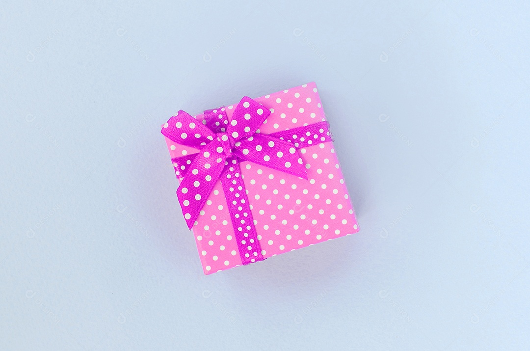 Caixa de presente rosa de bolinhas sobre fundo azul claro