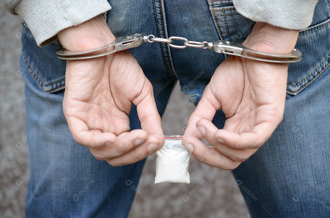 Traficante de drogas preso em algemas policiais com pequeno pacote de drogas de heroína