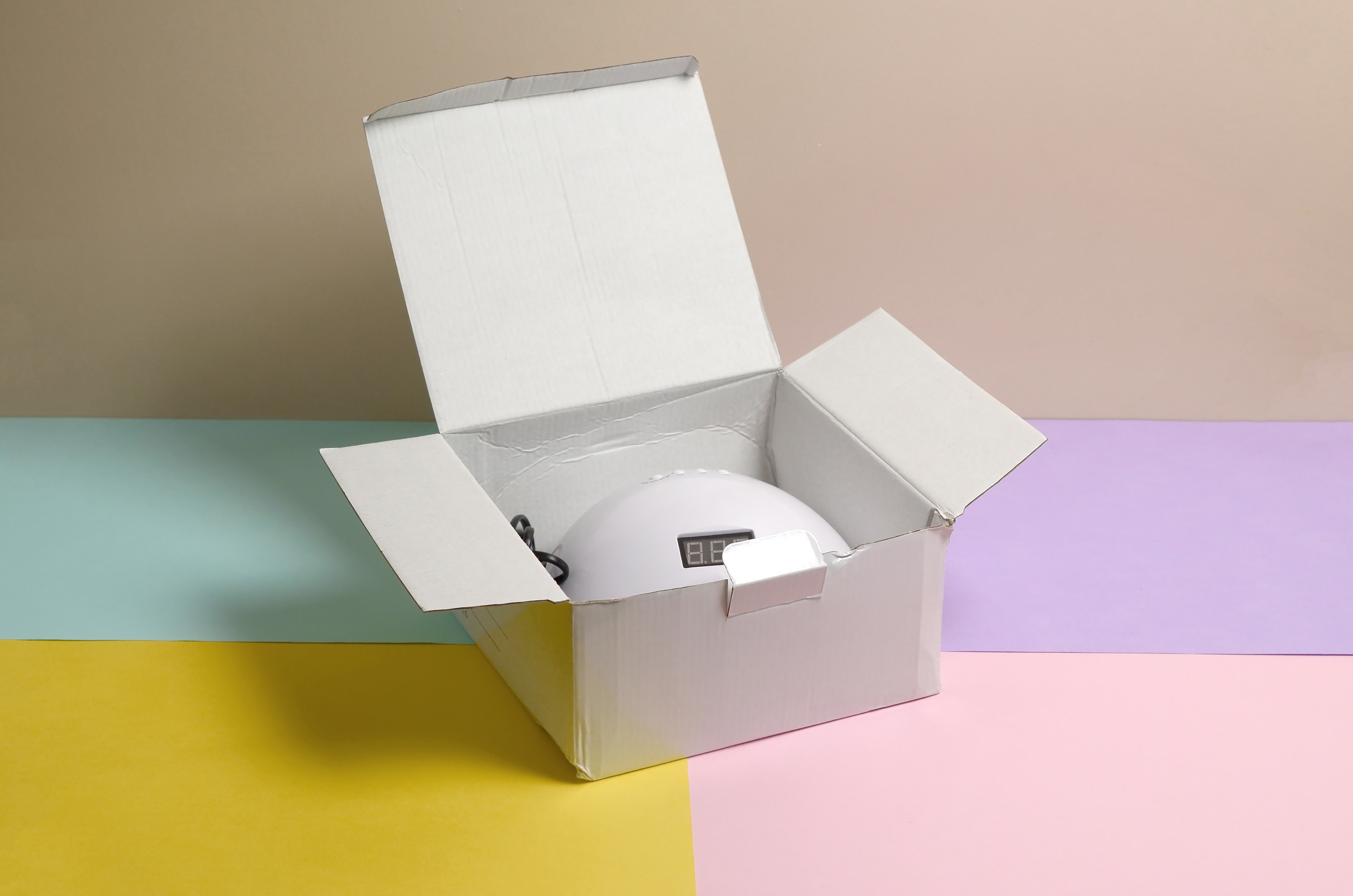 Caixa de papelão com lâmpada UV LED para unhas em mesa multicolorida pastel