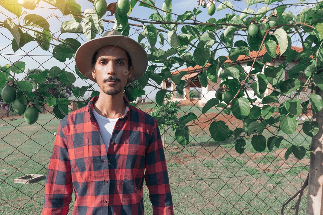 Fazendeiro negro de chapéu em fazenda plantação de maracujá ao fundo