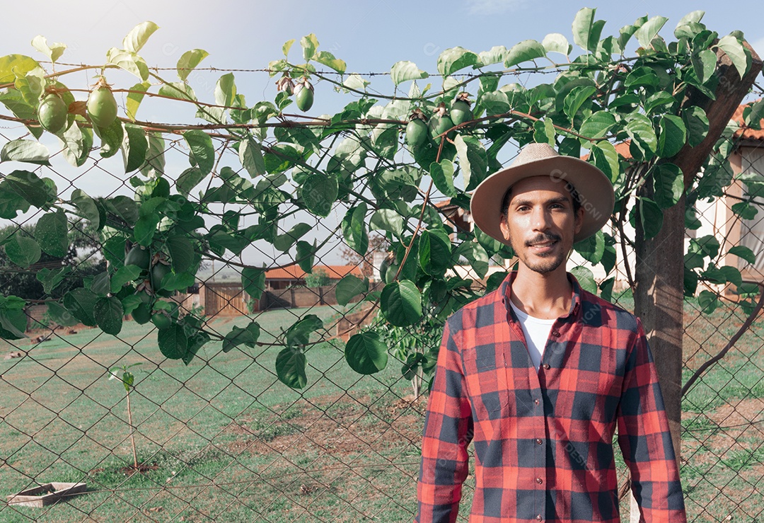 Fazendeiro negro de chapéu em fazenda plantação de maracujá ao fundo