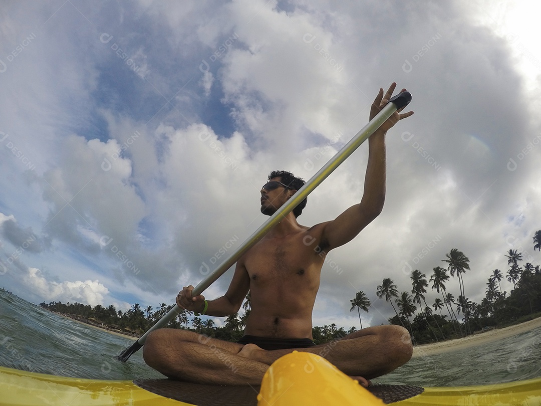 Homem jovem negro se divertindo praticando Stand Up paddle no mar