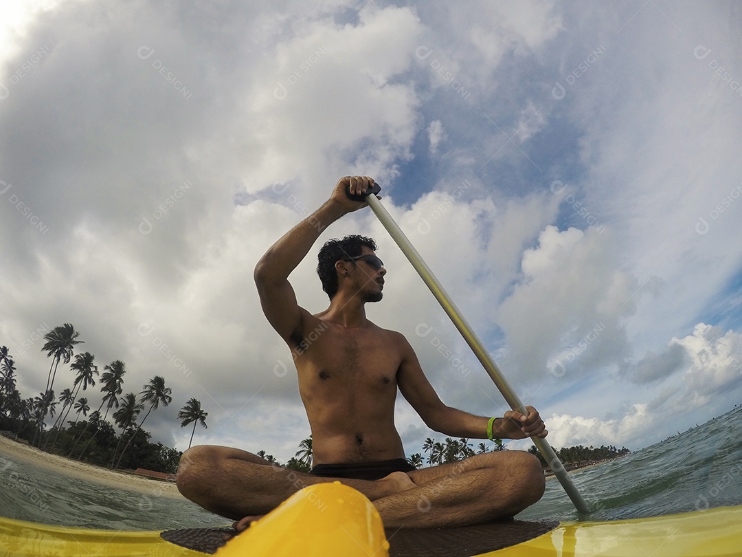 Homem jovem negro se divertindo praticando Stand Up paddle no mar