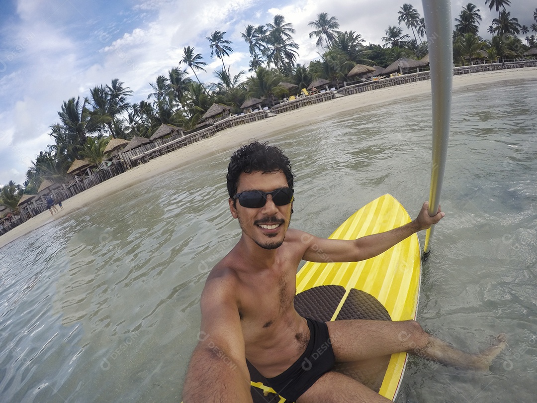 Homem jovem negro se divertindo praticando Stand Up paddle no mar