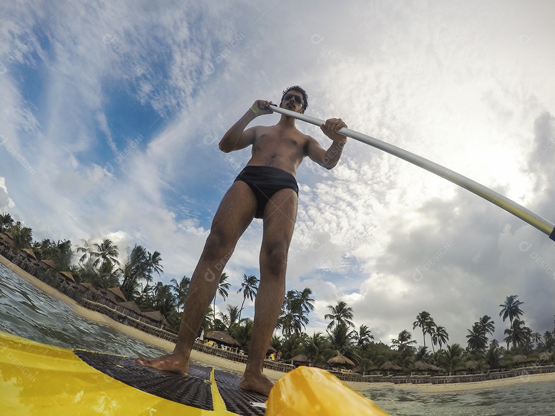 Homem jovem negro se divertindo praticando Stand Up paddle no mar