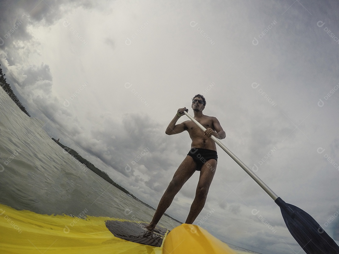 Homem jovem negro se divertindo praticando Stand Up paddle no mar
