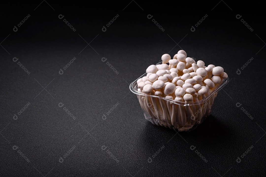 Pequenos cogumelos de faia comestíveis brancos com sal e especiarias sobre um fundo liso. Ingredientes para pratos asiáticos