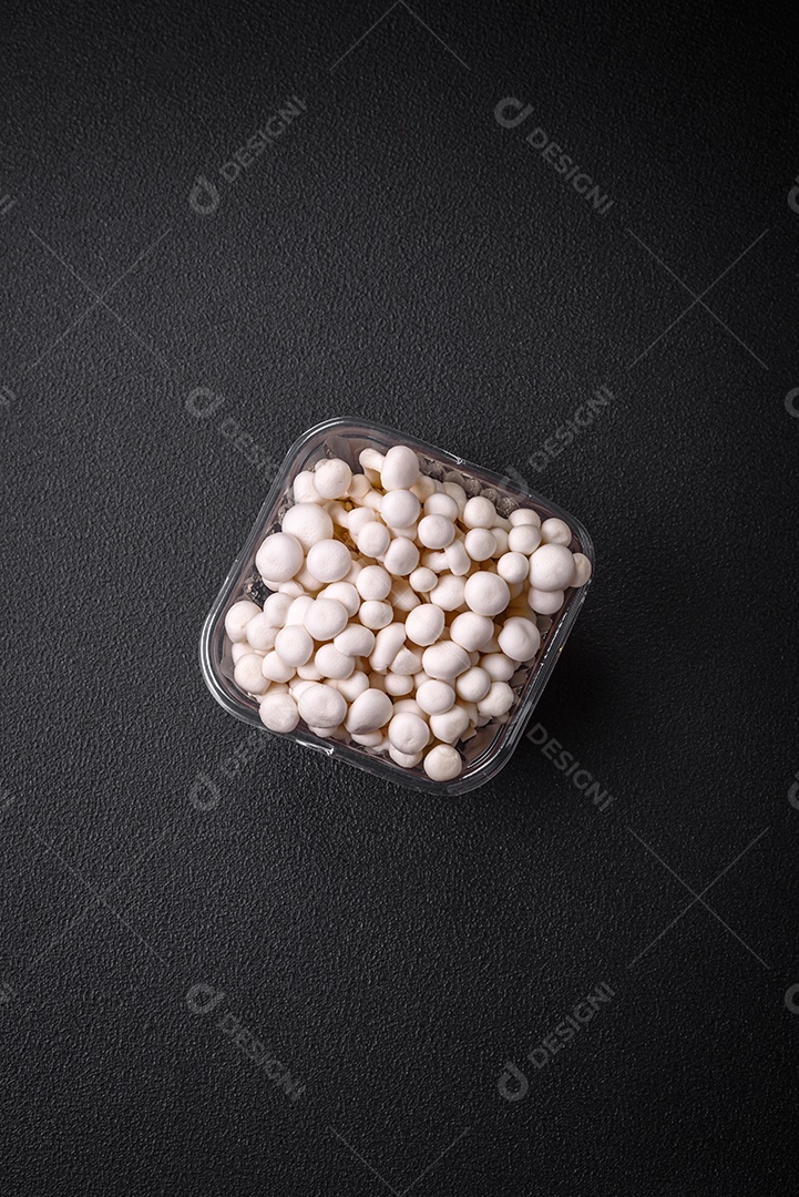 Pequenos cogumelos de faia comestíveis brancos com sal e especiarias sobre um fundo liso. Ingredientes para pratos asiáticos