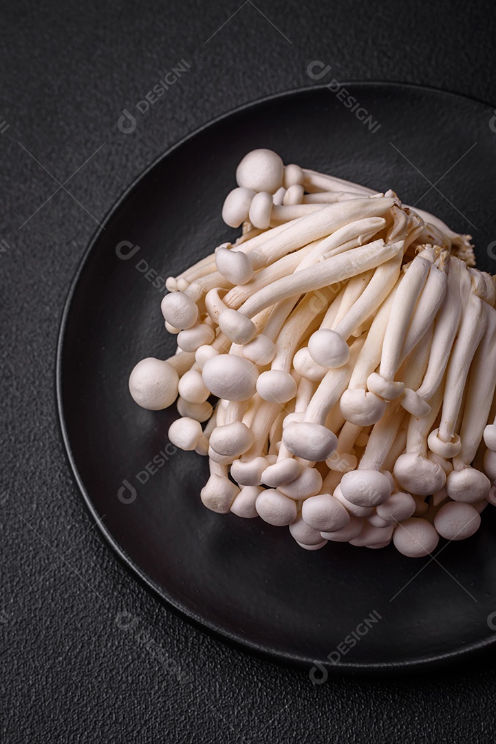 Pequenos cogumelos de faia comestíveis brancos com sal e especiarias sobre um fundo liso. Ingredientes para pratos asiáticos