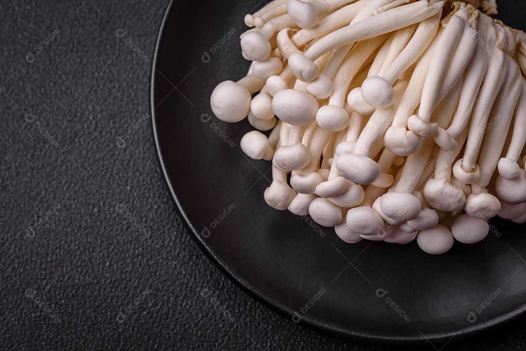 Pequenos cogumelos de faia comestíveis brancos com sal e especiarias sobre um fundo liso. Ingredientes para pratos asiáticos