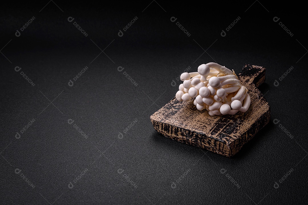 Pequenos cogumelos de faia comestíveis brancos com sal e especiarias sobre um fundo liso. Ingredientes para pratos asiáticos