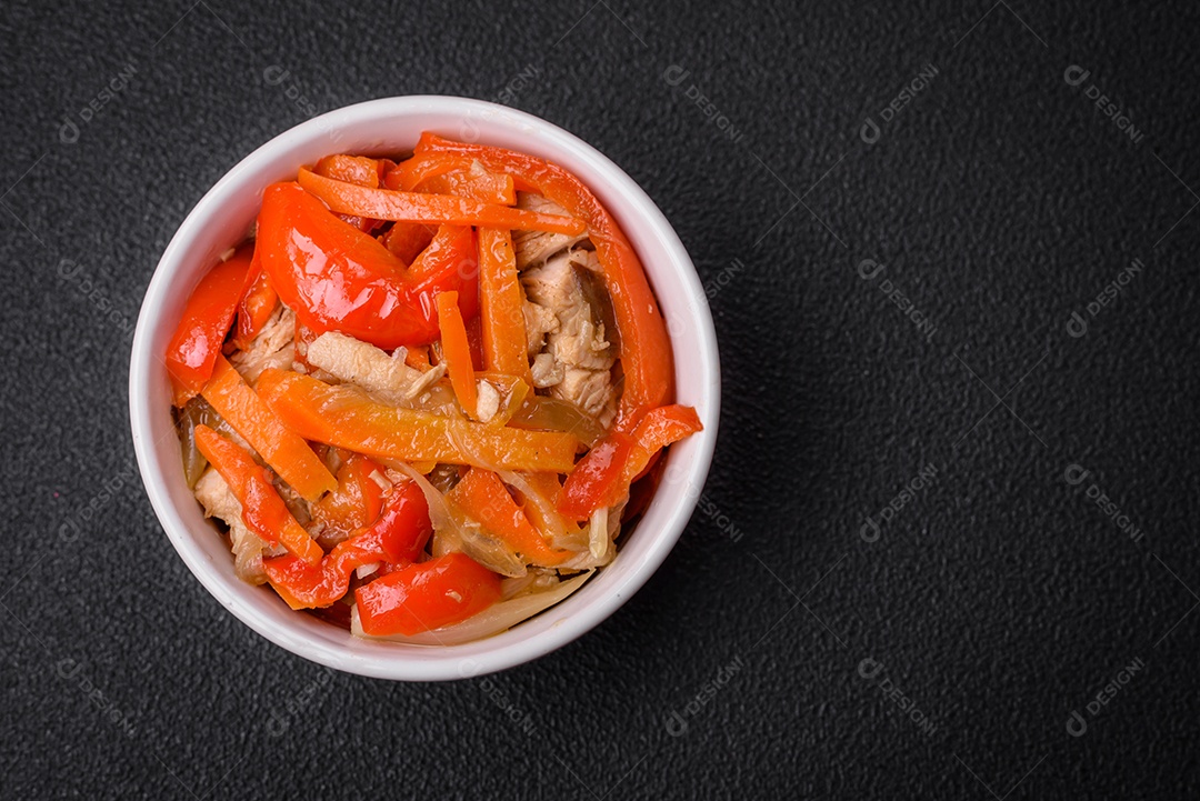 Delicioso ensopado fresco com frango ou peru com fatias de pimentão e cenoura com sal e especiarias sobre um fundo escuro de concreto