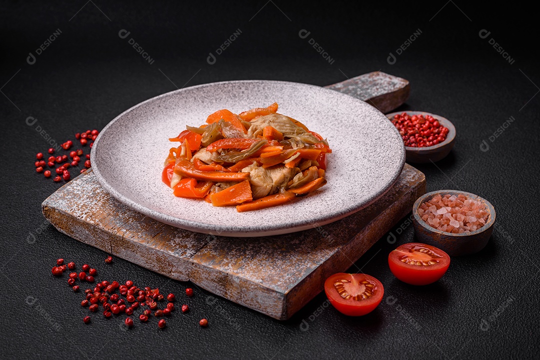 Delicioso ensopado fresco com frango ou peru com fatias de pimentão e cenoura com sal e especiarias sobre um fundo escuro de concreto