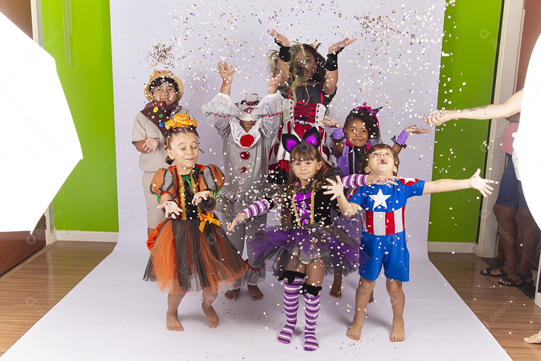 Crianças fantasiadas brincando com confetes.