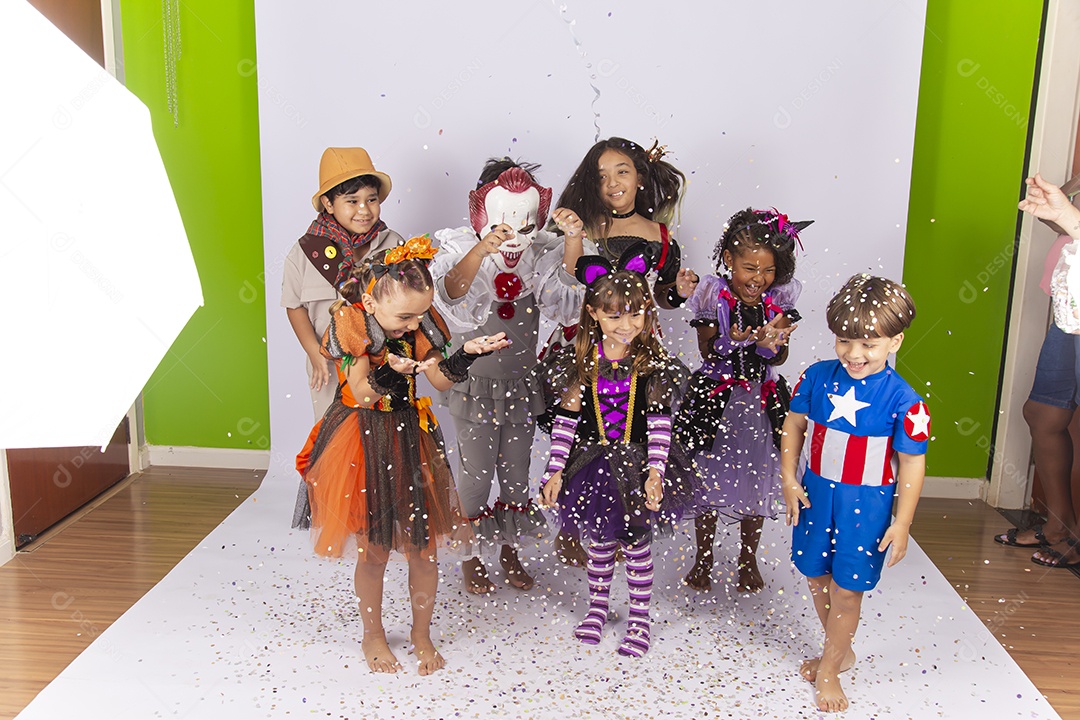 Crianças fantasiadas brincando com confetes.
