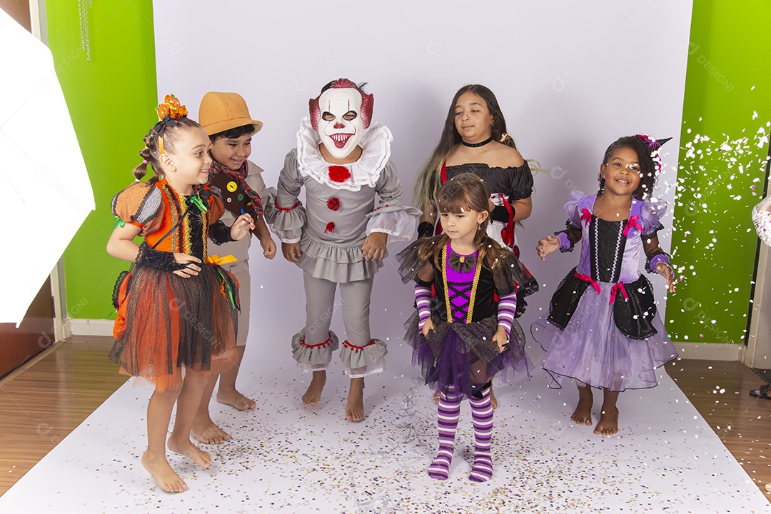 Crianças fantasiadas brincando com confetes.