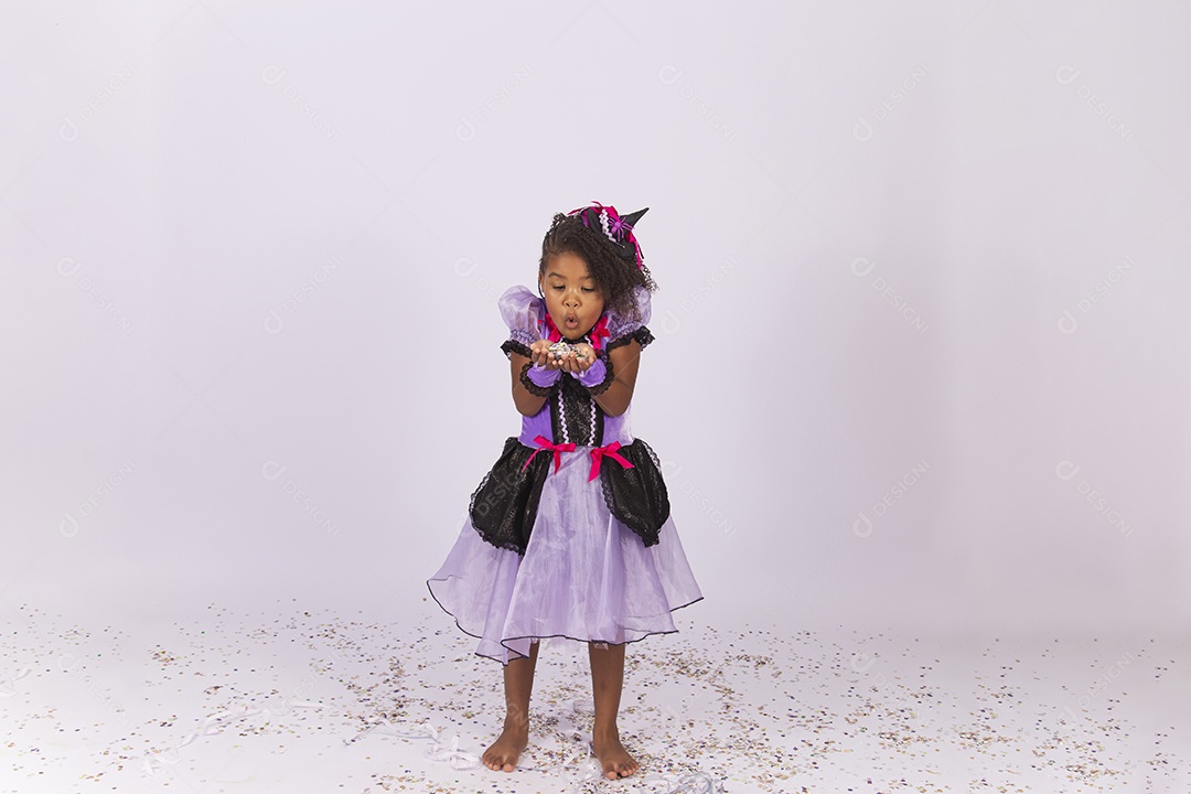 Linda menina fantasiada para o Halloween brincando com confetes.