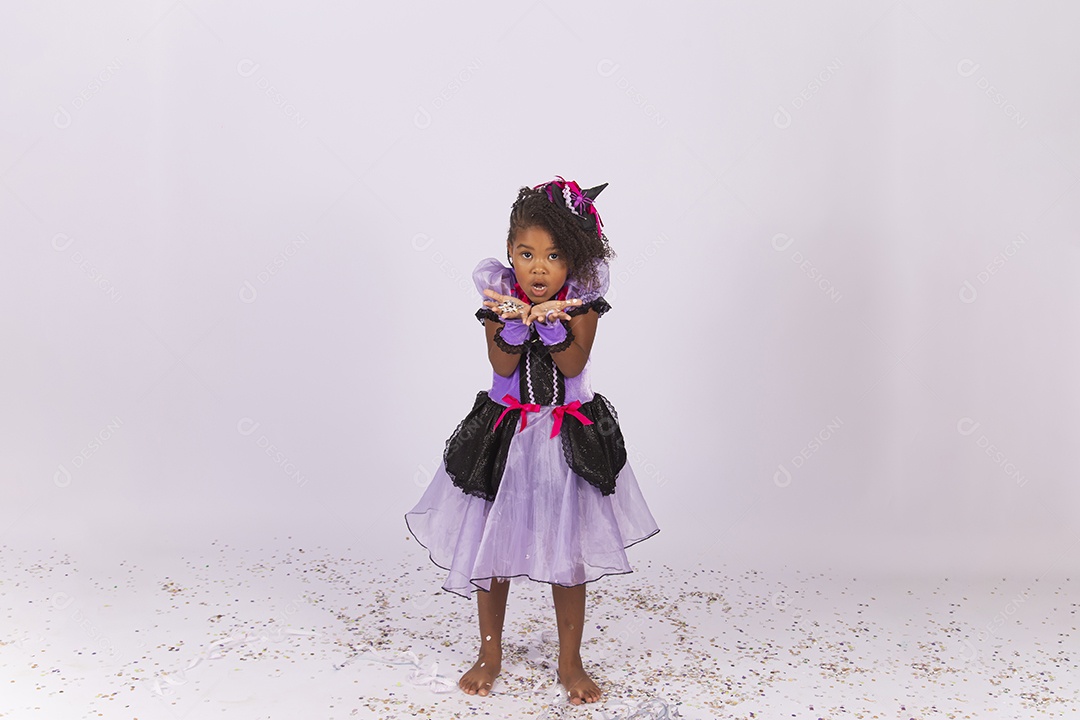 Linda menina fantasiada para o Halloween brincando com confetes.