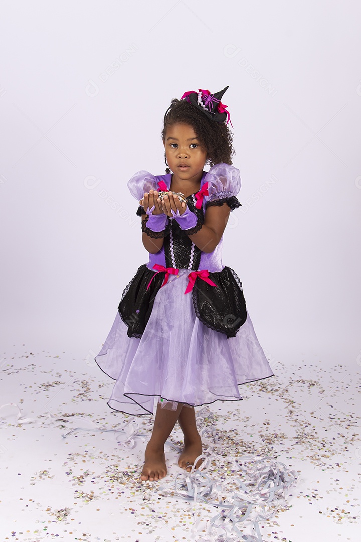 Linda menina fantasiada para o Halloween brincando com confetes.