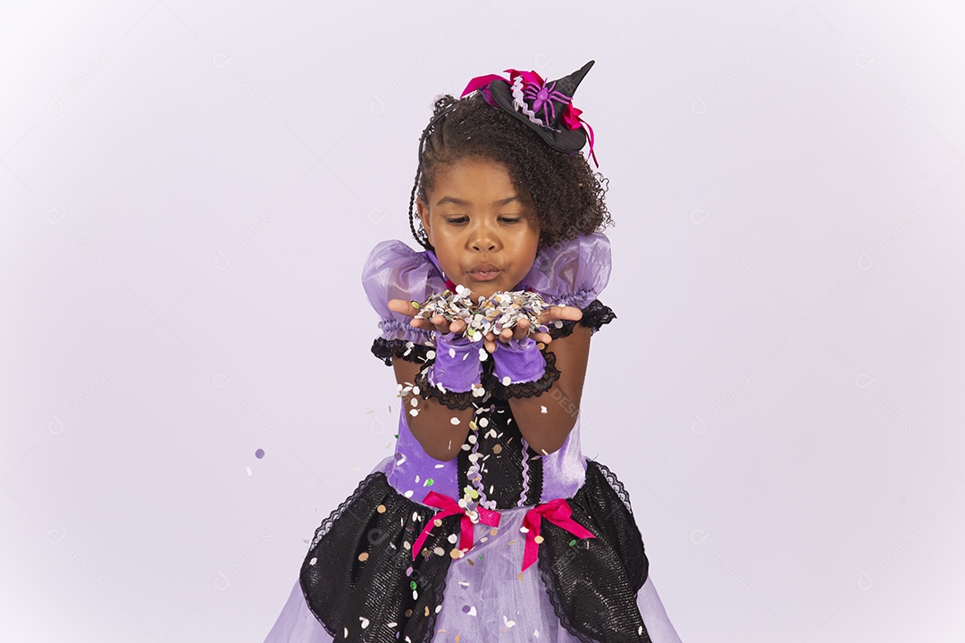 Linda menina fantasiada para o Halloween brincando com confetes.