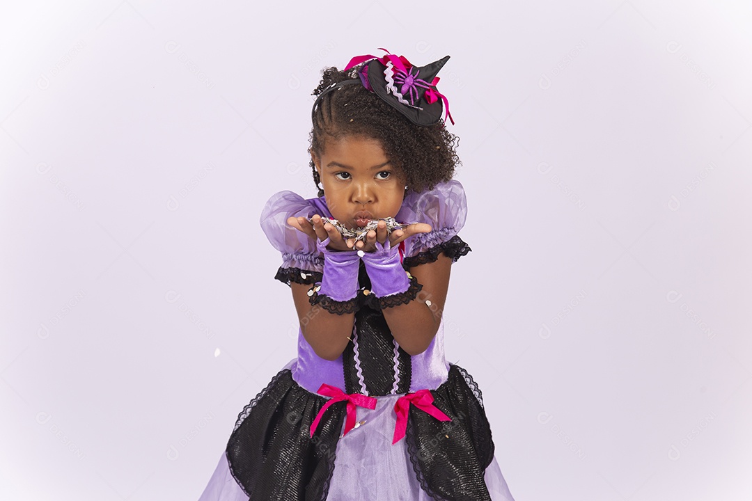 Linda menina fantasiada para o Halloween brincando com confetes.