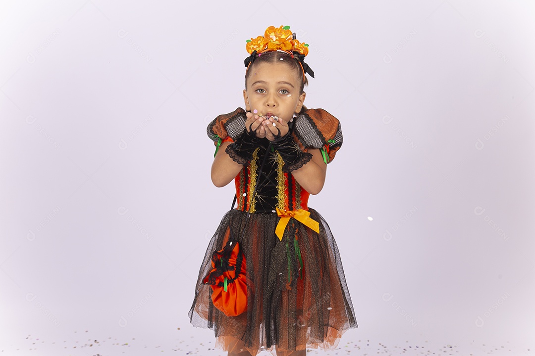 Linda menina fantasiada para o Halloween brincando com confetes.
