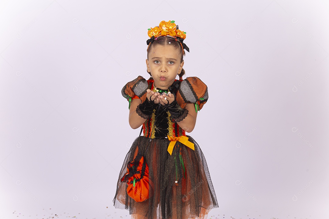 Linda menina fantasiada para o Halloween brincando com confetes.