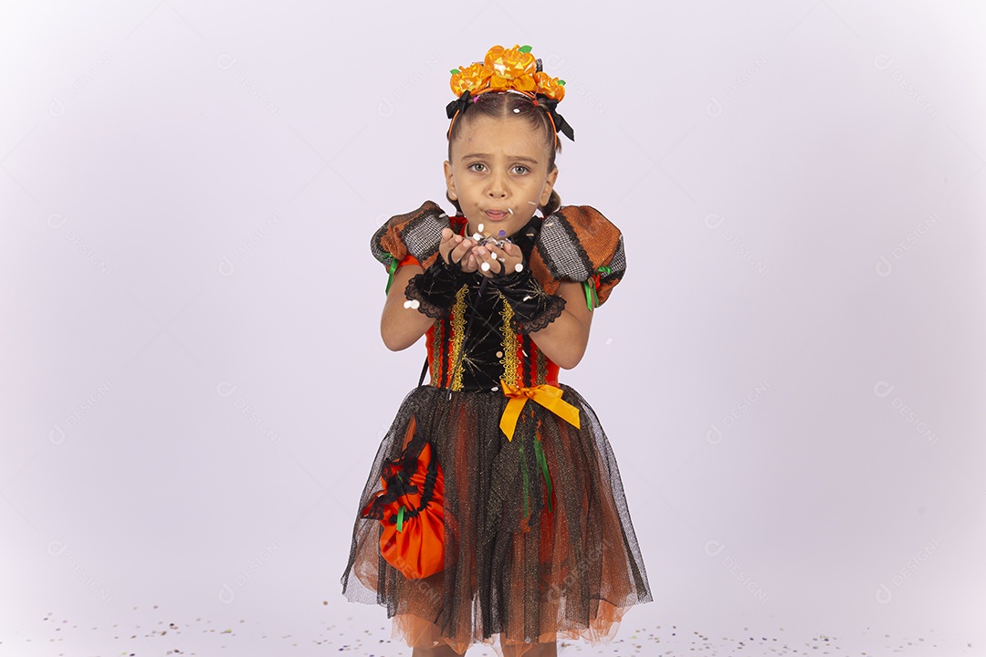 Linda menina fantasiada para o Halloween brincando com confetes.