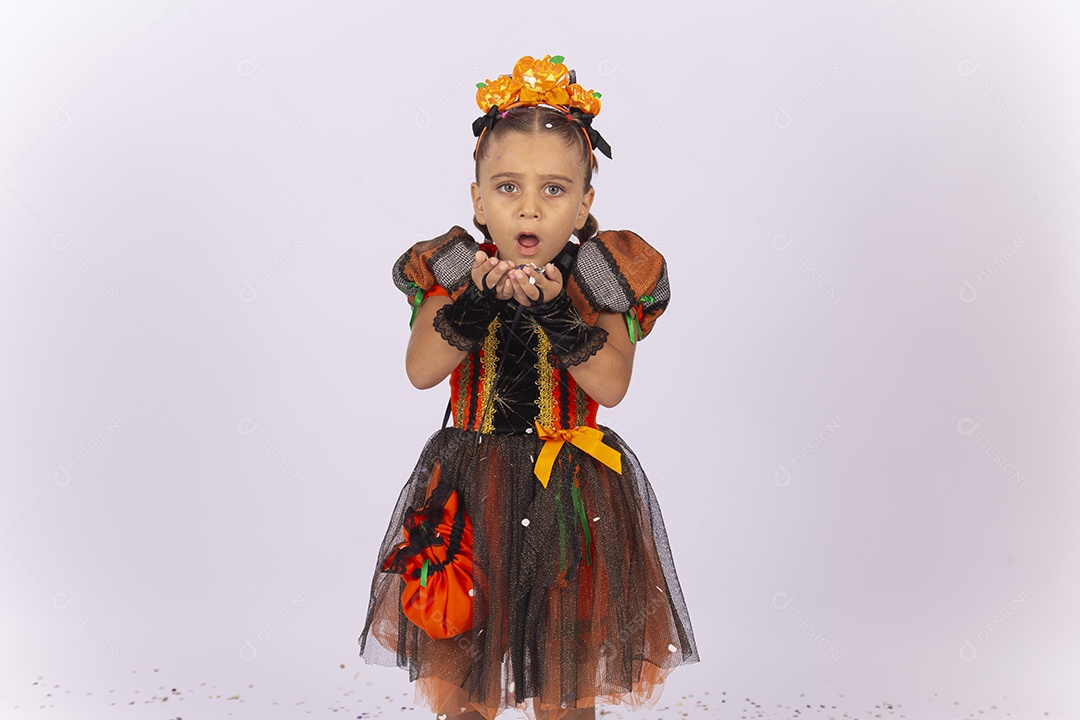 Linda menina fantasiada para o Halloween brincando com confetes.