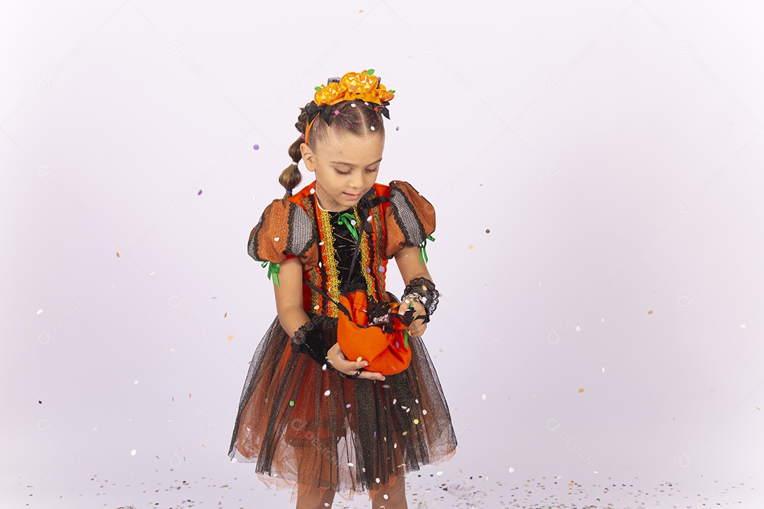 Linda menina fantasiada para o Halloween brincando com confetes.