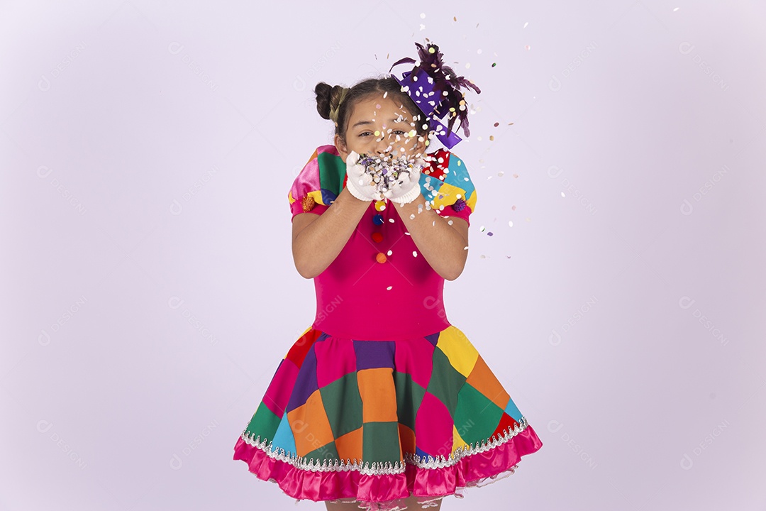 Linda menina fantasiada assoprando confetes sobre um fundo isolado branco.