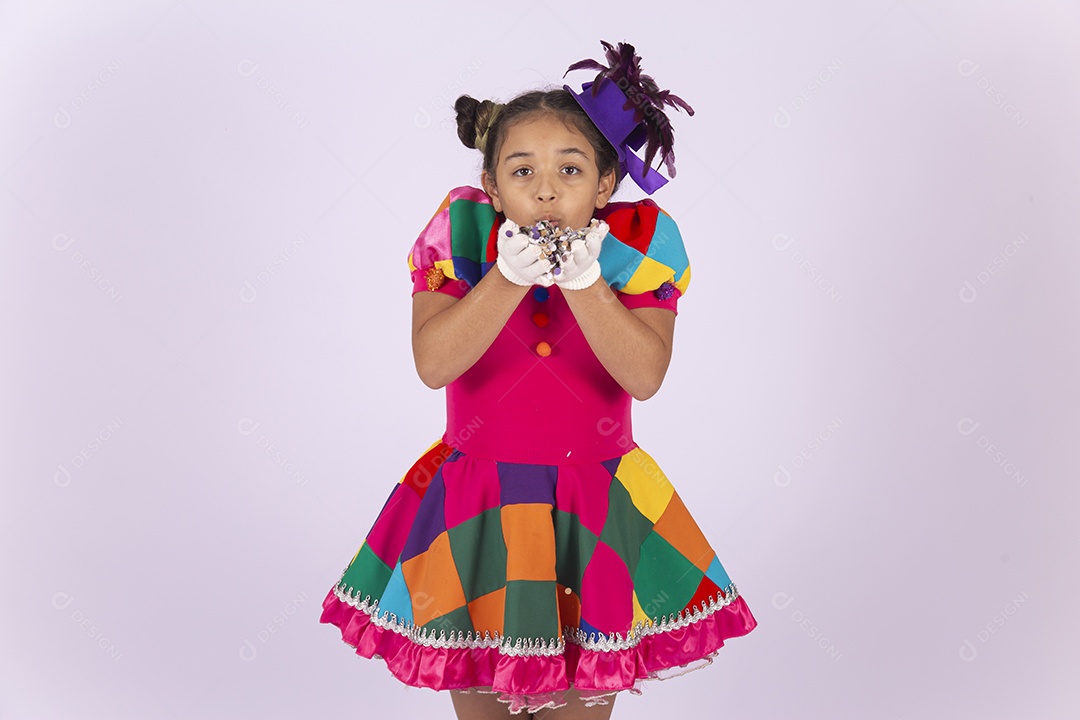 Linda menina fantasiada assoprando confetes sobre um fundo isolado branco.