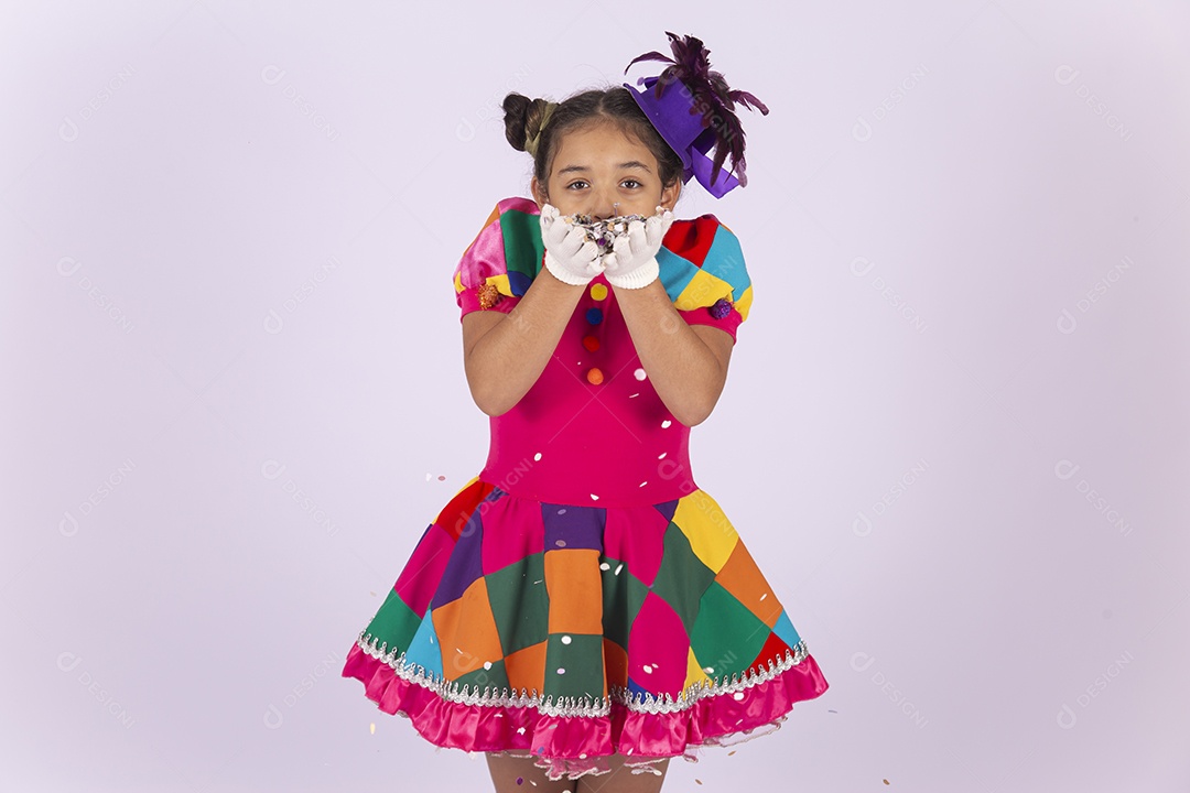 Linda menina fantasiada assoprando confetes sobre um fundo isolado branco.
