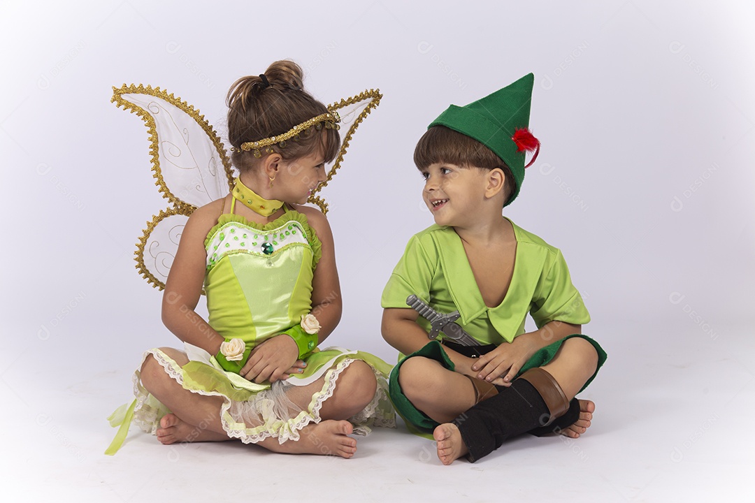 Crianças sentadas no chão fantasiadas sobre um fundo isolado branco.