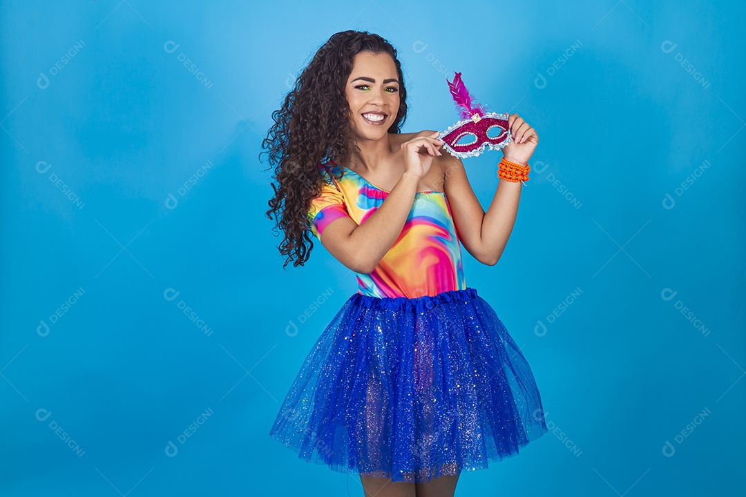 Mulher de cabelo cacheado fantasiada e segurando máscara de carnaval.