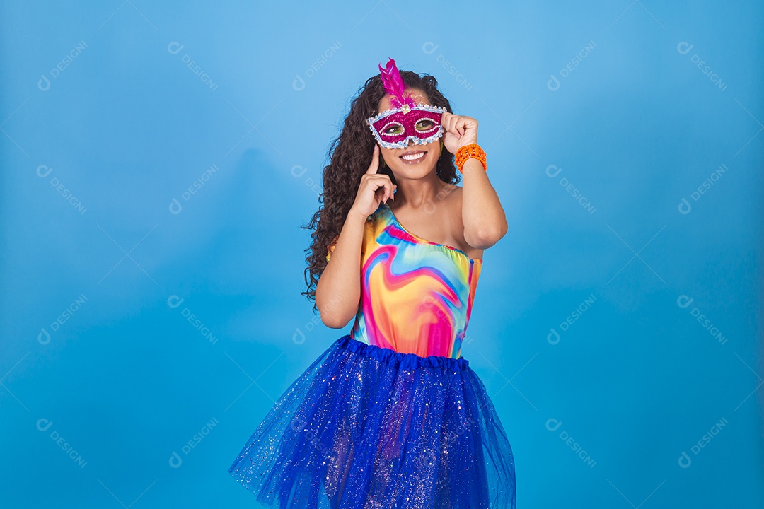 Mulher de cabelo cacheado com fantasia de carnaval sobre fundo isolado azul.