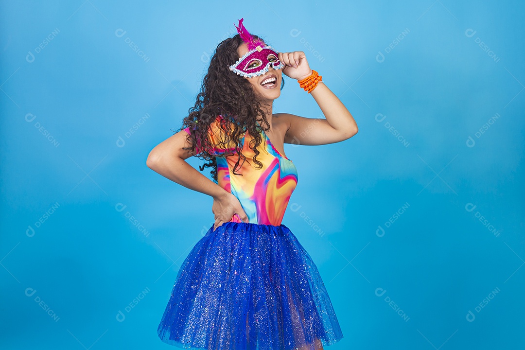 Mulher de cabelo cacheado com fantasia de carnaval sobre fundo isolado azul.
