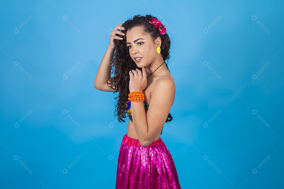 Mulher de cabelo cacheado com fantasia de carnaval sobre fundo isolado azul.