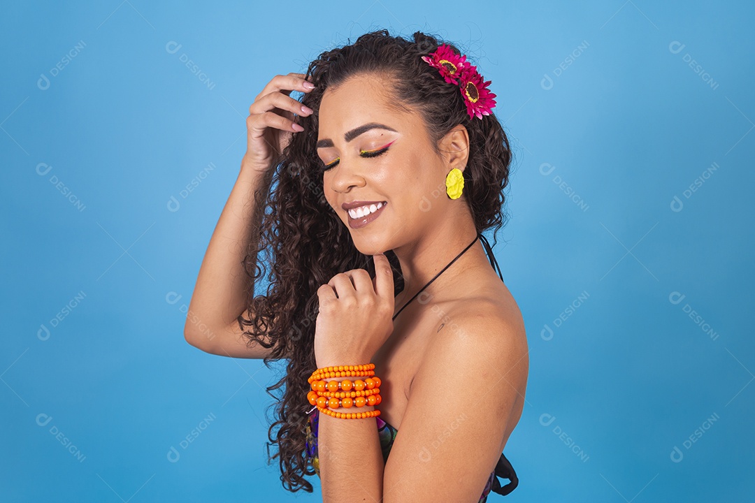 Linda mulher de cabelo cacheado sobre fundo isolado azul.