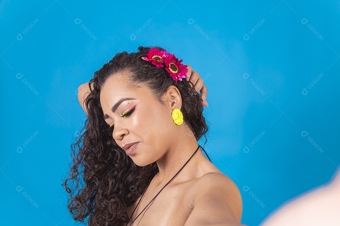 Linda mulher de cabelo cacheado sobre fundo isolado azul.