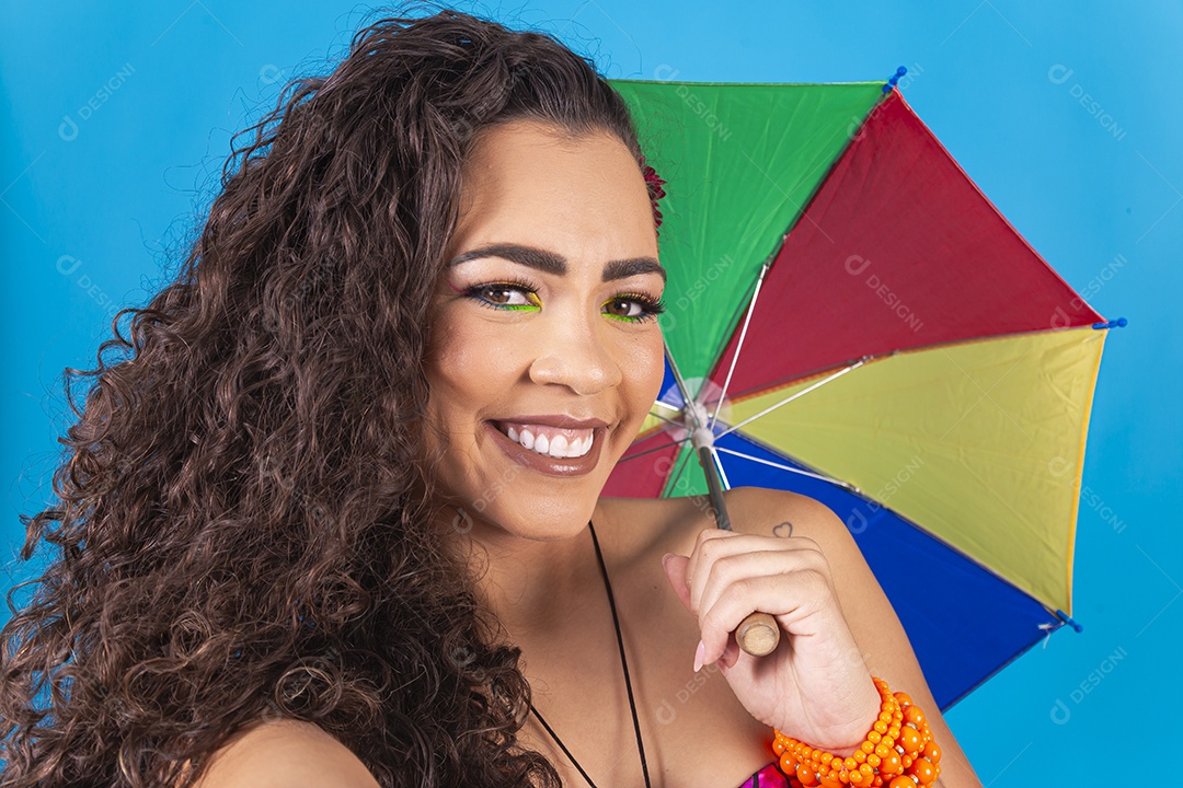 Mulher de cabelo cacheado segurando sombrinha de frevo.