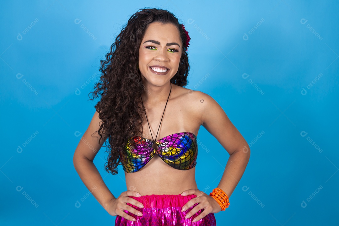 Mulher de cabelo cacheado com fantasia de carnaval sobre fundo isolado azul.